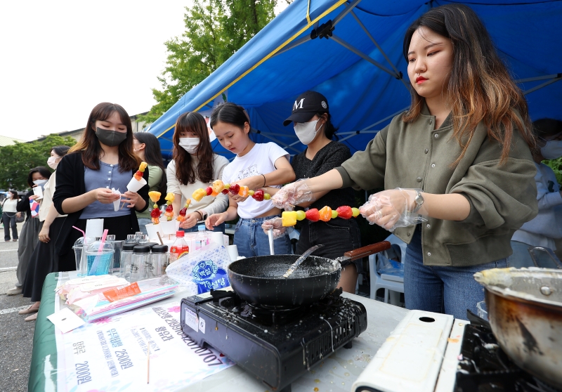 Students from the Department of Health Convergence at Ewha Womans University on Sept. 14 make tanghulu, a Chinese snack featuring fruit coated with a syrup made of sugar and starch, during the school-wide Daedong Festival. 